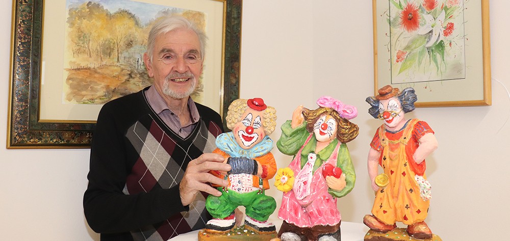 Künstler Sepp Fiedler mit den geschnitzten Clowns.